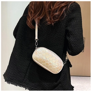 Detail of pearlescent PU leather crossbody bag with fish scale quilted texture on model