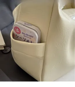 Dettaglio della borsa a tracolla in pelle PU crema con trama a pieghe e tasca laterale extra