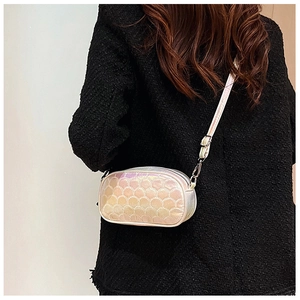 Detail of silver fish-scale textured crossbody bag worn over a black tweed coat