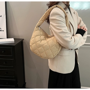 Detail of cream quilted puffy hobo bag with wave patterns and padded shoulder strap