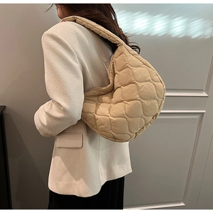 Detailed close-up of quilted nylon shoulder bag in khaki with soft puffer texture