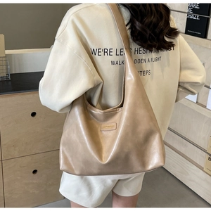Khaki PU leather tote bag shown on model in a cozy indoor minimalist setting