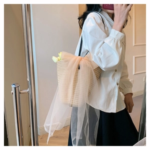 Close-up of woven straw bucket bag with large peach mesh bow and yellow tulip decor
