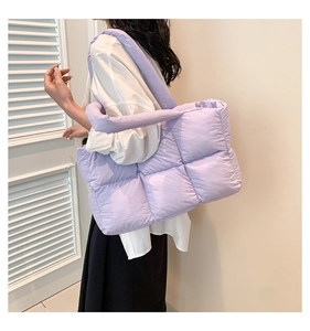 Gros plan d'un sac cabas matelassé violet clair porté à l'épaule par un mannequin