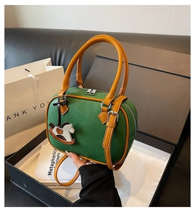Detail of green PU leather Boston bag with horse charm in a stylish gift box setup