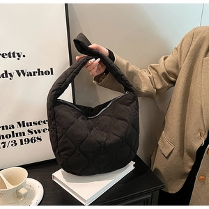 Fashionable black quilted nylon tote bag styled with a minimalist outfit and coffee