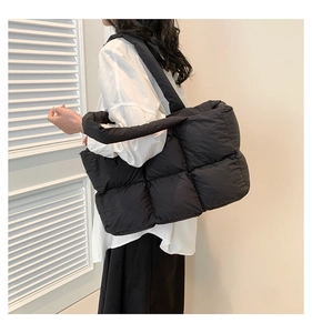 Modèle portant un sac cabas en coton matelassé noir avec bandoulières rembourrées et grand volume