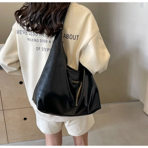 Detailed view of a black PU leather hobo bag with natural folds and metal logo
