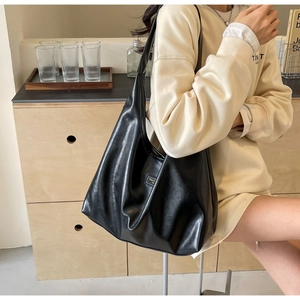 Close-up of black PU leather hobo bag with a rectangular logo plate and soft texture