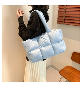 Detail of light blue quilted puffer shoulder bag with a metallic nylon finish and spacious design