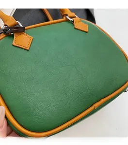 Close-up of litchi pattern PU leather in dark green and orange with silver metal hardware