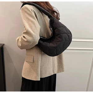 Detail of black quilted nylon shoulder bag with wavy texture and zipper closure