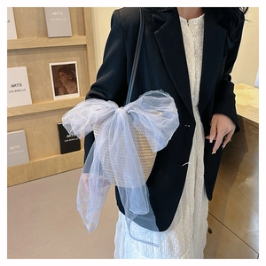 Detail of woven straw bucket bag featuring a large light blue sheer organza bow decoration