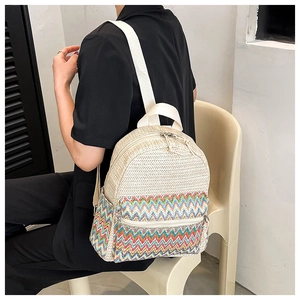 Detailed side view of woven straw backpack with colorful zigzag patterns and canvas straps