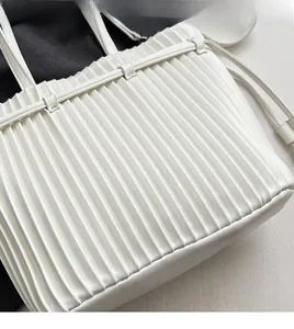 Close-up of pleated white PU leather handbag showing soft texture and accordion design