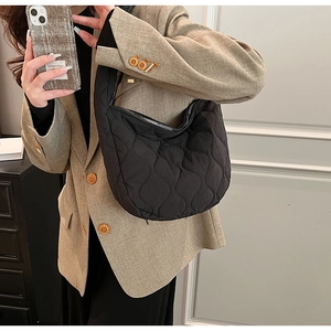Side view of black quilted nylon shoulder bag on model with silver zipper detail