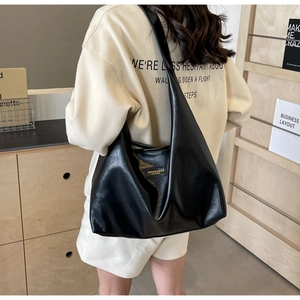 Detail of minimalist black PU leather tote bag with square logo patch on wide shoulder strap