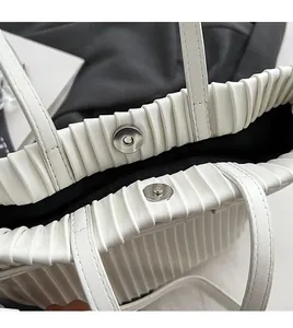 Close-up of elegant pleated white tote bag with silver magnetic metal closure hardware