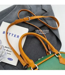 Detail of adjustable orange strap and dual zippers on a green Boston bag over a suit
