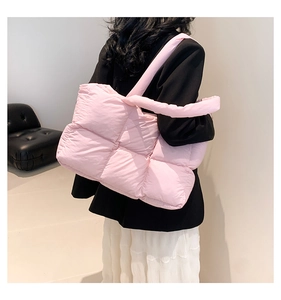 Rear view of a model wearing a pink quilted puffer tote bag with large square stitching