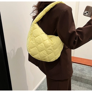 Detailed view of pale yellow quilted nylon shoulder bag with soft bubble texture