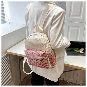 Detail of hand-woven beige straw backpack with vibrant zigzag patterned pocket and straps
