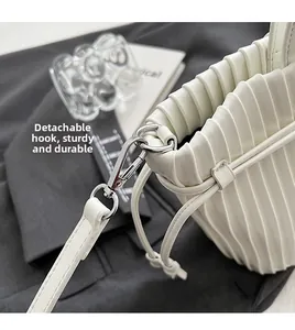 Detail of cream PU leather handbag featuring detachable silver metal rings and pleated design