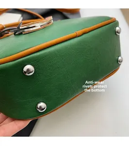 Detail view of emerald green bag bottom with four silver protective metal rivets