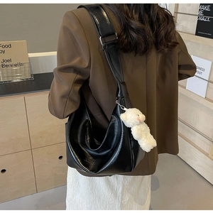 Dettaglio della borsa hobo in pelle PU nera lucida con orsetto di peluche su modella