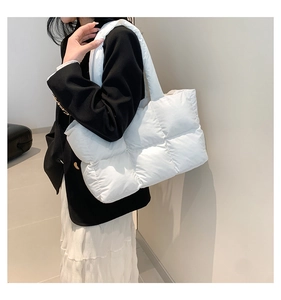 Close-up of white quilted down tote bag with padded handles and puffy texture