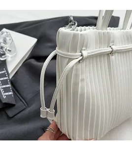Detailed view of the pleated white PU leather texture with silver metal buckles and stitching