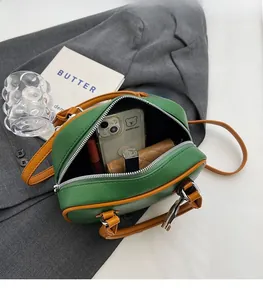 Detail of spacious interior of green and tan pebbled leather crossbody bag with items