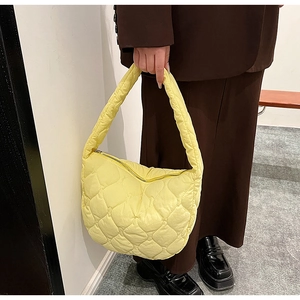 Detail of a bright yellow quilted nylon bubble bag paired with a dark brown suit