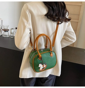 Deep green Boston bag with brown straps and rocking horse charm on a model