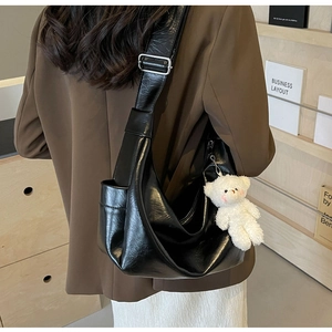 Dettaglio della borsa hobo nera con trama stropicciata retrò e ciondolo a orsetto