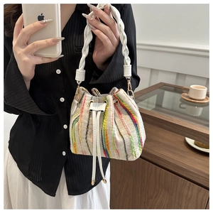 Detail shot of woven bucket bag featuring colorful vertical stripes and white drawstrings