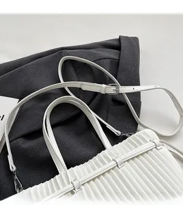 Detailed view of the fine vertical pleats and silver metal buckle on the white PU bag