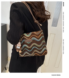 Detail of knitted crossbody bag with wave pattern and cute plush bear charm