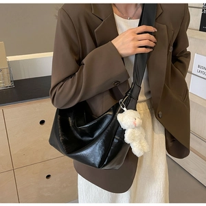 Borsa hobo a mezzaluna in pelle lucida indossata con ciondolo a forma di orsetto