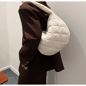 Close-up of cream quilted nylon tote bag with stylish puffy cloud texture on a model