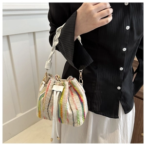 Detail of colorful knitted striped bucket bag with drawstring and woven handle