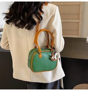 Chic green and tan PU leather Boston bag shown on model with stylish horse charm detail