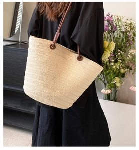 French woven straw tote bag with brown leather straps shown on a model for daily use