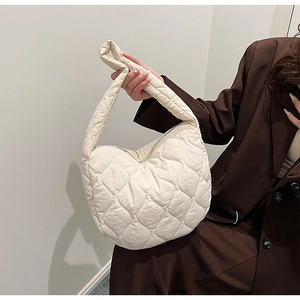 Close-up of beige quilted nylon crescent bag with textured diamond stitching and zipper