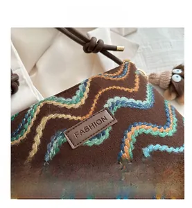 Detail of wave embroidery on brown crossbody bag with fashion leather patch and rope strap