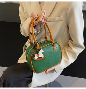 Detail of dark green pebble leather handbag with vintage rocking horse charm and silver zipper