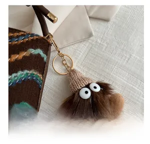 Detailed macro view of a brown plush monster bag charm with large eyes and a gold clasp