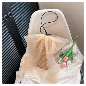 Elegant beige straw bucket bag with a champagne tulle bow and black shoulder strap