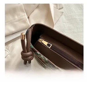 Close-up of knit crossbody bag with golden metal zipper and brown leather drawstrings