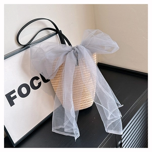 Minimalist woven bucket bag with large grey mesh bow and black shoulder strap in a stylish set